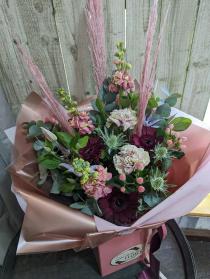 Hand tied bouquet in greens, pinks and red tines.